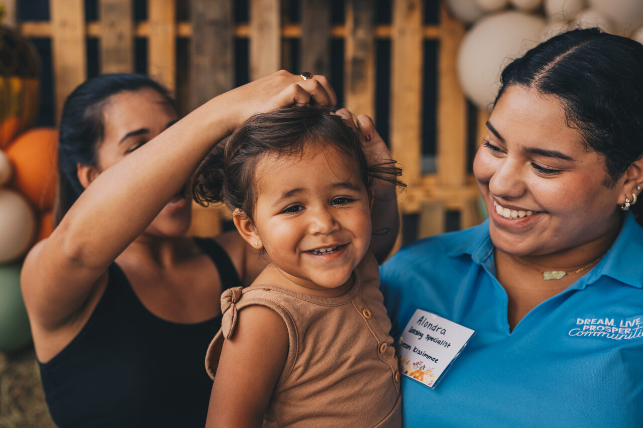 A resident and her daughter with an on-site team member at a community event